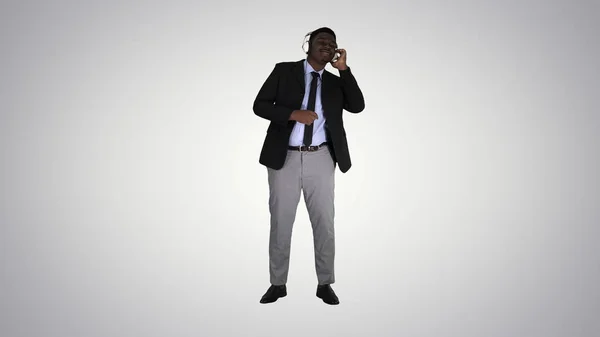 Чорний бізнесмен танцює до музики в навушниках на градієнтному фоні . — стокове фото