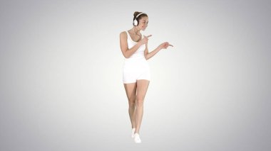Yürüyüş ve degrade arka plan üzerinde müzik büyüleyici fitness kız.