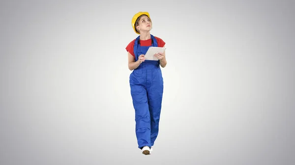 Woman construction worker with tablet checking construction site on gradient background. — Stock Photo, Image