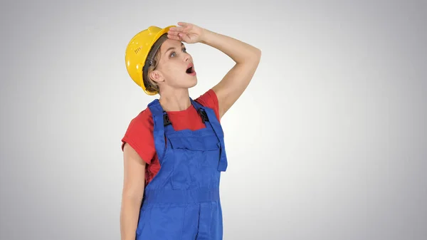 Engineer construction worker woman looking up amazed on gradient background.