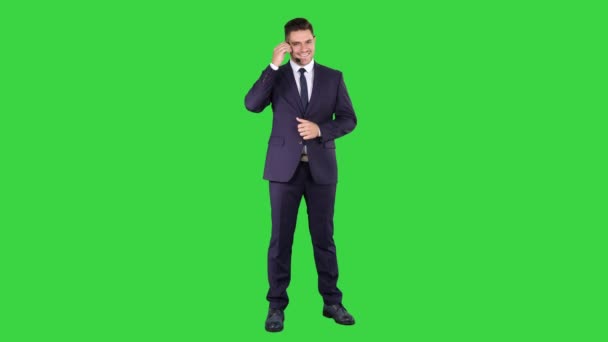 Bonito empresário com fone de ouvido olhando para a câmera e sorrindo em uma tela verde, Chroma Key . — Vídeo de Stock