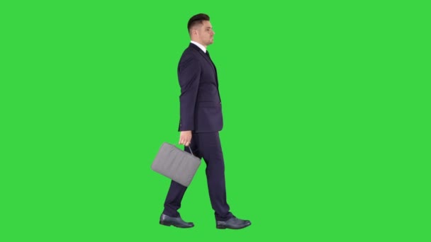 Stilig affärsman i en kostym promenader med en portfölj på en grön skärm, Chroma Key. — Stockvideo
