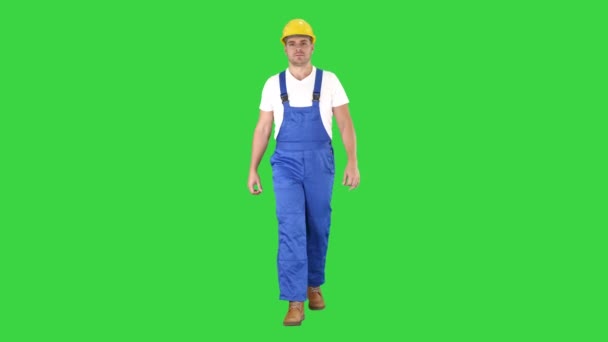 Wandelen werknemer in gele helm op een groen scherm, Chroma Key. — Stockvideo