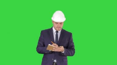 Yeşil Ekran, Chroma Key üzerinde not defterine giysi ve kask yürüyüş ve not yazma Mühendisi.