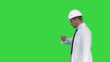 Yeşil Ekranda geç kalma gibi saate bakan hardhat giyen mimar Portresi, Chroma Key.