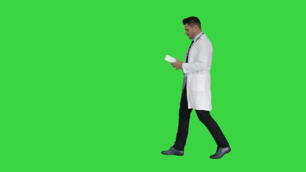 Mature doctor in whitecoat describing new pills in box on a Green Screen, Chroma Key. — Stock Video