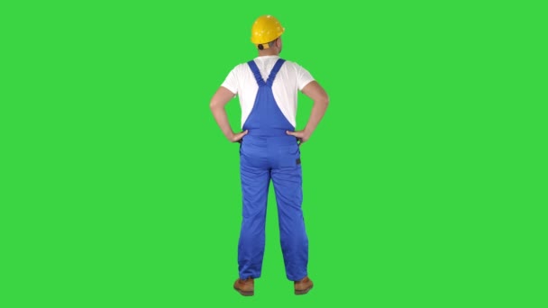 Ingénieur dans le casque de construction debout avec les mains sur les hanches regardant autour d'un écran vert, Chroma Key . — Video