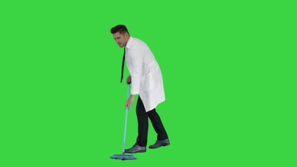 Людина в білому халаті підмітання підлозі і говорити на зеленому екрані, ключ до кольоровості. — стокове відео