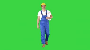 İnşaat işçisi mavi baskılar ile yürüyüş ve Yeşil Ekranda kameraya gülümseyerek, Chroma Anahtar.