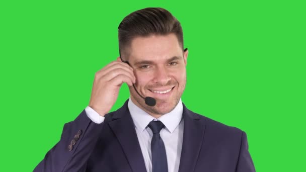 Przystojny biznesmen z zestawem słuchawkowym patrząc w kamerę i uśmiechając się na zielonym ekranie, Chroma Key. — Wideo stockowe