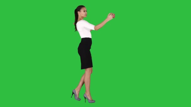 Όμορφο κορίτσι που παίρνει μια selfie και περπατάει σε μια πράσινη οθόνη, πλήκτρο αποχρώσεων. — Αρχείο Βίντεο