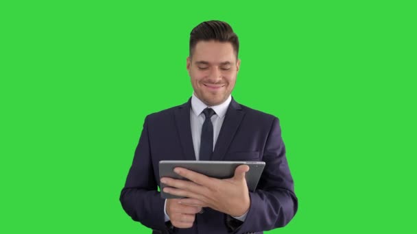 Mature handsome emotional businessman watching funny video in popular website on digital tablet on a Green Screen, Chroma Key. — Stock Video