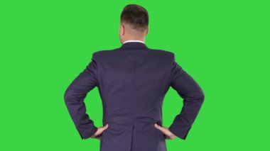 Bir yeşil ekran üzerinde kalça eller ile etrafında bakıyor işadamı, Chroma anahtar.