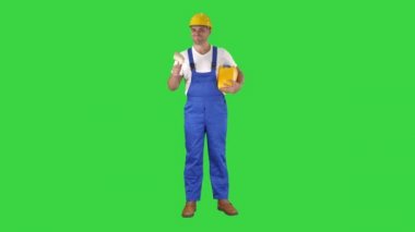 İşçi tutan boya fırçası yeşil ekranda kameraya gülümsüyor, chroma key.
