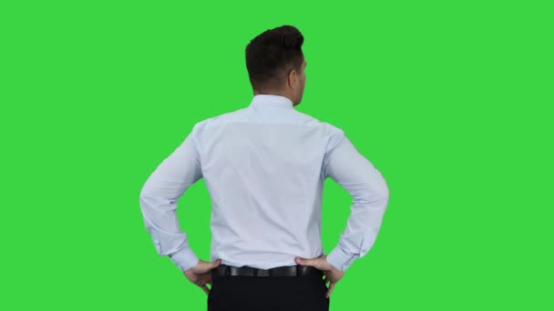 Hombre de camisa azul mirando a su alrededor comprobando algo con las manos en las caderas en una pantalla verde, Chroma Key . — Vídeos de Stock