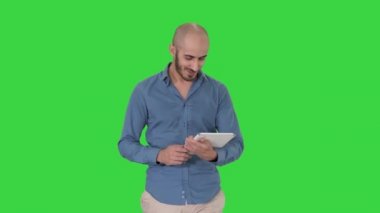 Arap adam yürüyüş ve yeşil ekranda tablet sörf internet kullanarak, Chroma anahtar.