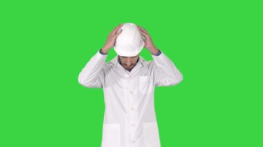 Beyaz cüppeli Arap mühendis Yeşil Ekranda Güvenlik konseptine sert şapka koyarak, Chroma Key.