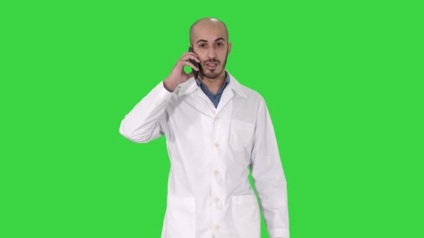 Professioneller Arzt, der auf einem grünen Bildschirm mit einem Mobiltelefon spricht, Chroma-Schlüssel. — Stockvideo