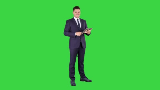 Ekspresyjny młody biznesmen z tabletem prezentujący coś przesuwając na zielonym ekranie, Chroma Key. — Wideo stockowe