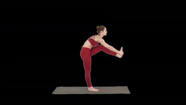 Mooie jonge fitte vrouw in sportkleding doet sport oefening, buigen in variatie van Utthita Hasta Padangusthasana, Dandayamana-Janushirasana, Alpha Channel — Stockvideo