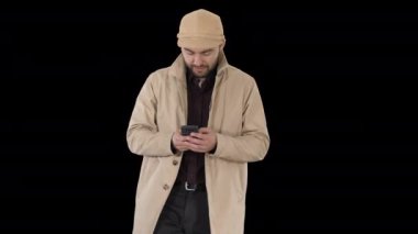 Pelerinli genç adam Alpha Channel 'da telefonla mesajlaşıyor.