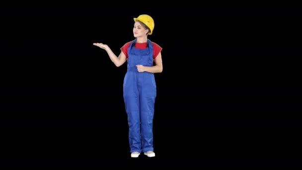 Зрелая женщина-инженер представляет продукт, указывающий в сторону, канал Альфа — стоковое видео