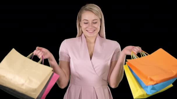 Opgewonden mooie jonge dame staande op zoek camera tonen boodschappentassen, Alpha Channel — Stockvideo