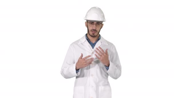 Scientist in white robe and helmet presenting pointing to side with hand and explaining to camera on white background. — Stock Video