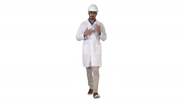 Scienziato in vestaglia bianca e casco che presenta indicando a lato con mano e spiegando alla fotocamera su sfondo bianco. — Video Stock