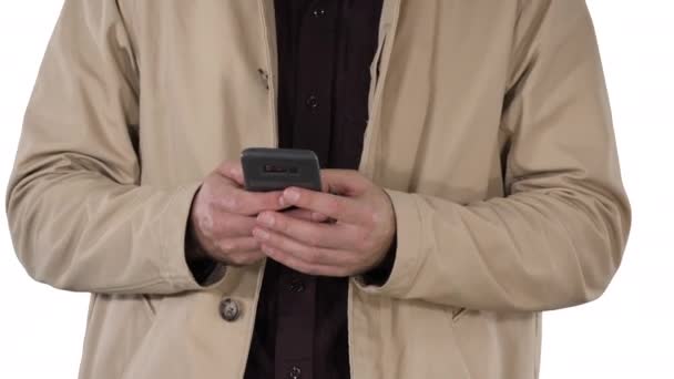 Человек в плаще с помощью мобильного смартфона на белом фоне. — стоковое видео