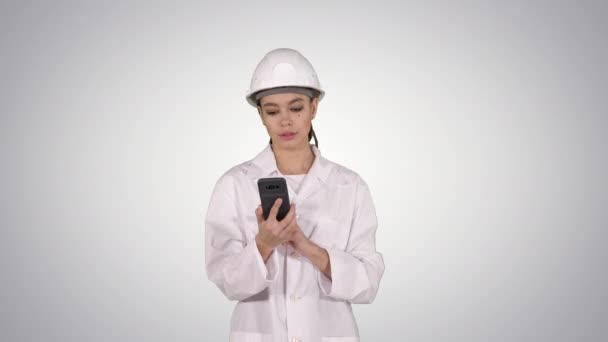 Woman engineer talking on the phone while walking on gradient background. — Stock Video