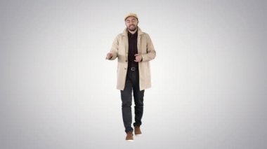 Trençkotlu genç adam arka planda selam veriyor..