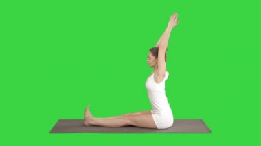 Genç, çekici bir kadın yoga yapıyor, öne eğilip egzersiz yapıyor, paschimottanasana pozu veriyor, spor yapıyor, spor kıyafetlerini yeşil ekranda giyiyor, Chroma Key..