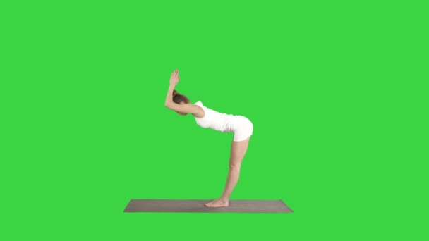 Красивая модель делает упражнения йоги стоя в Уттанасане с ладонями на задней части лодыжек на зеленом экране, хрома ключ . — стоковое видео