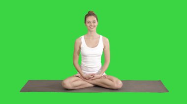 Yoga minderin üzerinde oturan ve Yeşil Ekranda kameraya konuşan beyaz klöter güzel kadın, Chroma Key.