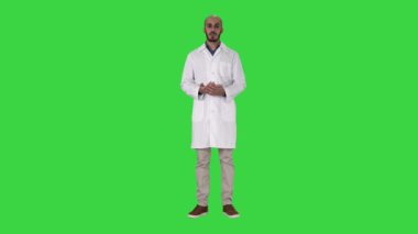 Tıbbi ceket Arap doktor adam konuşma ve El ile yeşil ekran, Chroma Key bir şey sunan.