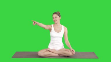 Nilüfer çiçeğinde oturan genç çekici kadın Yeşil Ekran 'da konuşurken bir şeyi ya da birini işaret ediyor, Chroma Key.