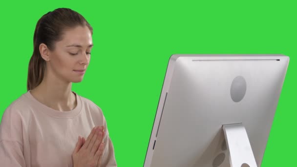 Aantrekkelijke vrouw in een stoel aan tafel met computer mediteren op een groen scherm, Chroma Key. — Stockvideo