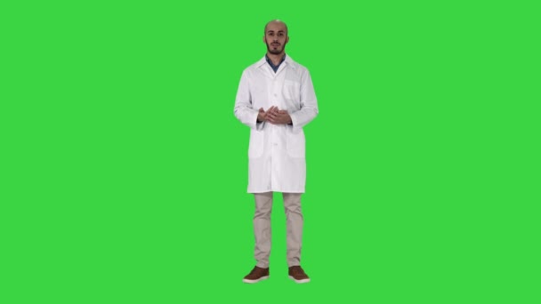 Médico árabe con abrigo médico hablando y presentando con la mano algo en una pantalla verde, Chroma Key . — Vídeos de Stock