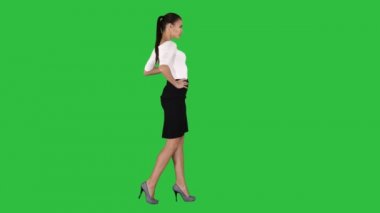 Şık kıyafet yürüyüş güzel genç kadın, bir yeşil ekran, Chroma Key kalçalarına üzerinde ellerimi.