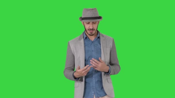 Hombre alegre positivo con estilo de moda que usa camisa casual y sombrero de sol caminando y hablando con la cámara en una pantalla verde, Chroma Key . — Vídeo de stock