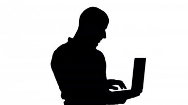 Siluet Genç Ortadoğulu işadamı, dizüstü bilgisayarı elinde tutarken ayakta duruyor ve daktilo yazıyor..