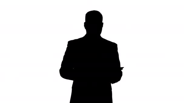 Silhouette Businessman camminando e scorrendo pagine sul suo computer tablet e cercando di fotocamera che presenta qualcosa. — Video Stock