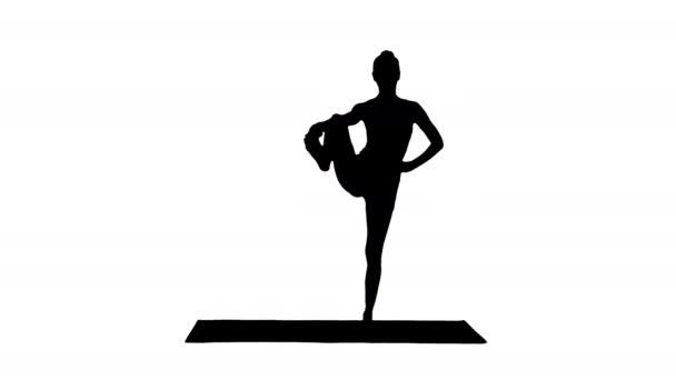 Silhouet mooi glimlachend gelukkig jonge vrouw doen yoga oefening op mat, staand in Vrksasana houding, boom pose. — Stockvideo