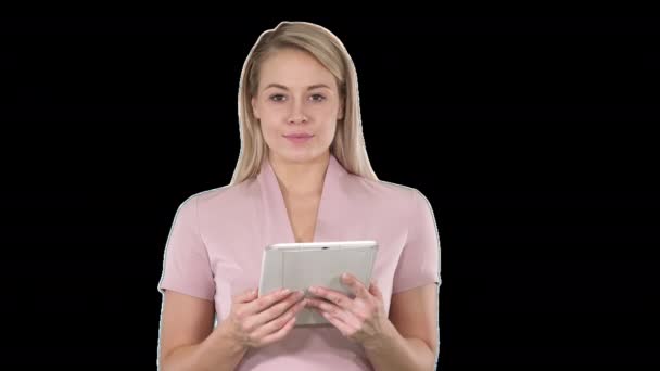 Střední záběr krásná žena pomocí tabletu obrací stránky a při pohledu do kamery, alfa kanál — Stock video