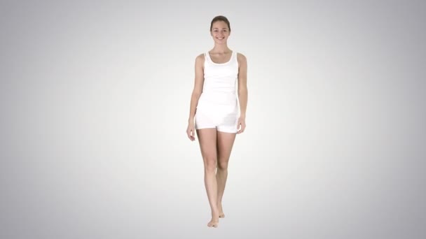 Jovem mulher sexy andando e sorrindo vestida com shorts gradiente e t-shirt no fundo gradiente. — Vídeo de Stock