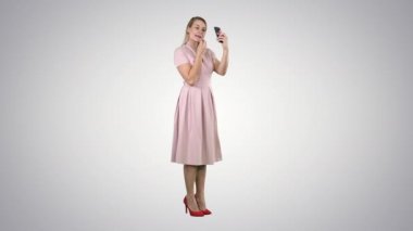Ruj süren bir kadın telefonunun gradyan arka planına bakıyor..