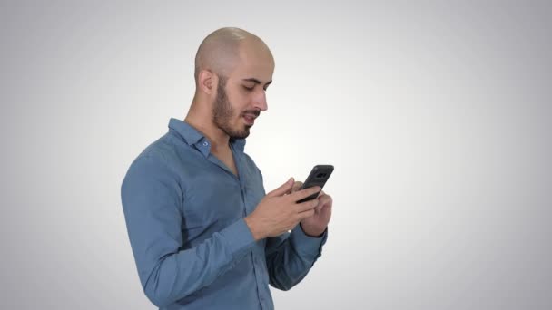 Homme d'affaires arabe occasionnel utilisant le téléphone et souriant sur fond de dégradé . — Video