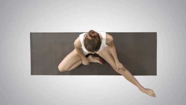 Woman folding legs in to lotus pose on gradient background. — Stock Video