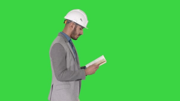 緑の画面、クロマキーを歩いている間、若い建築家は教科書やノートを読む. — ストック動画
